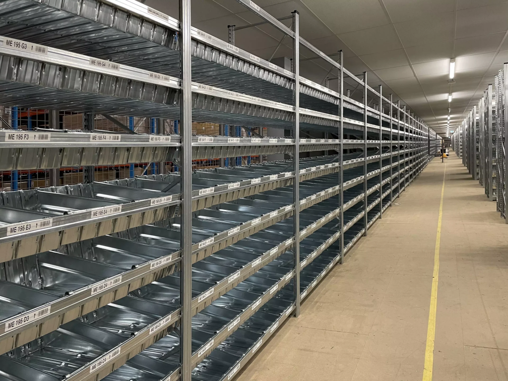 Close-up view of long Unirack shelving bays with labelled shelf locations and metal storage bins for stock organisation.
